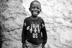 African child smiling with shirt that says Join us